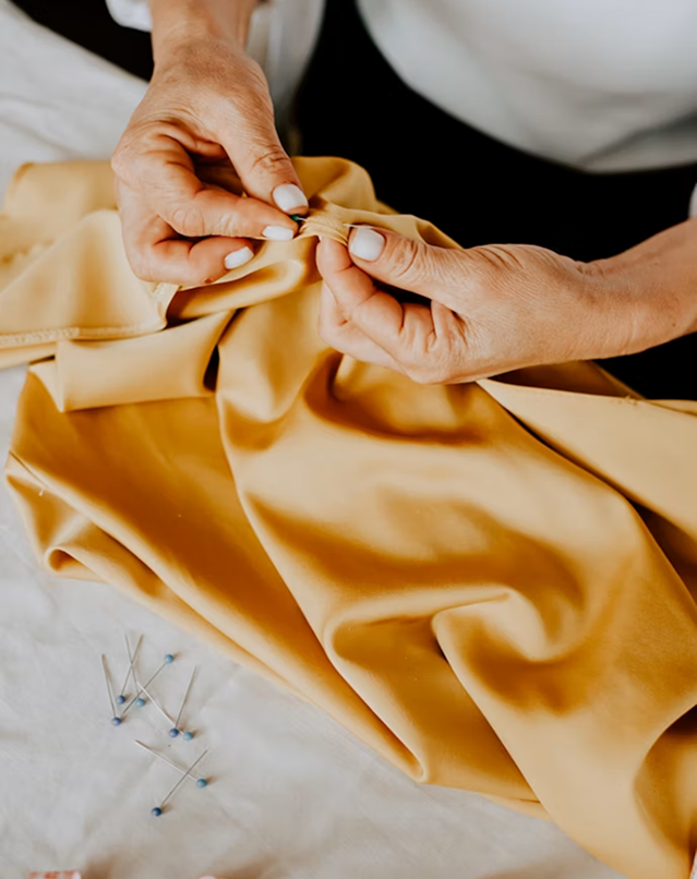Ensemble cousu posé et mains d'artisan en train d'épingler le tissu